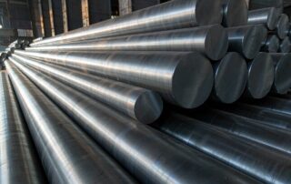 Large diameter 4330V quenched and tempered alloy steel round bars stacked in a steel mill with machined cut ends